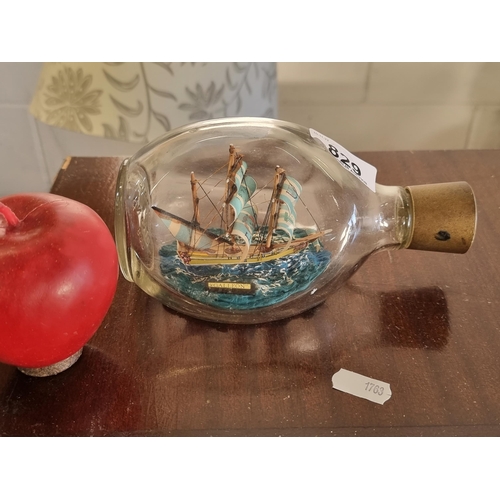 829 - A charming ship in a bottle, consisting of a miniature model of the Gallion ship in a dimpled Hague ... 