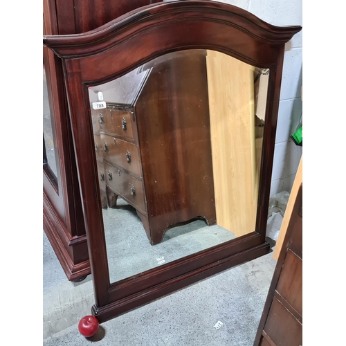 788 - An elegant wall mirror. With bevelled glass and an arched pediment. In a lovely mahogany frame with ... 