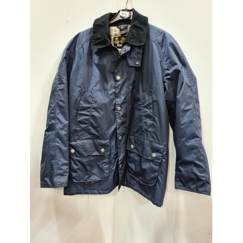 816 - A Barbour waterproof rain jacket in a navy blue, with four pockets to front and a handsome check lin... 