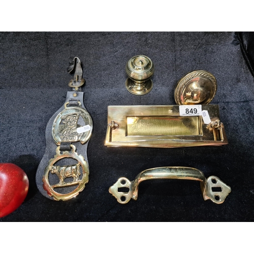 849 - Five recently polished brass items including a letterbox cover, two horse brasses on a leather strap... 