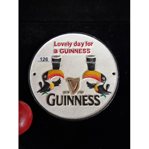 126 - A round, cast metal wall plaque advertising Guinness and featuring two toucans and text in high reli... 