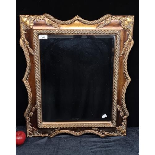 106 - A very heavy ornate bevelled wall mirror with rope edge detail and a burnished gilt finish.