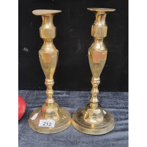 212 - A pair of tall, brass candlesticks featuring a panelled urn stem, a striking set would make a statem... 