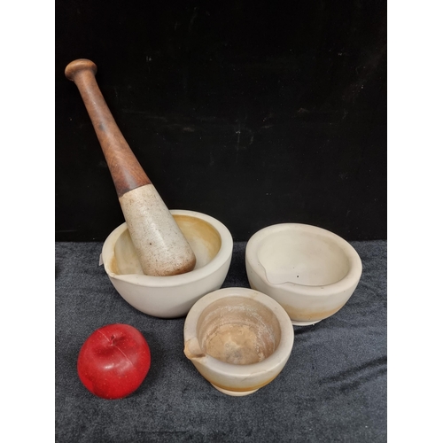 306 - Three very heavy ceramic mortars and one heavy pestle in white.