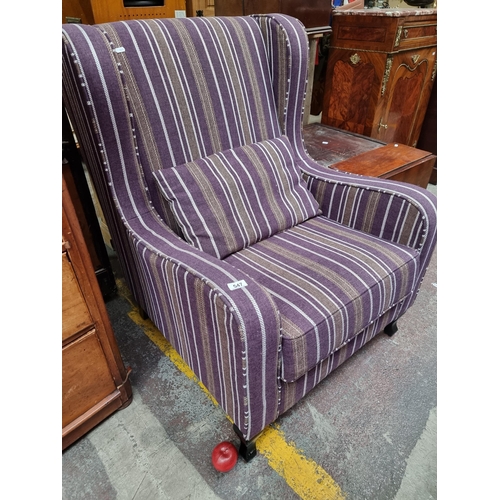 547 - Star Lot : A generous armchair with subtle wingback details. Upholstered in a purple, brown and silv... 