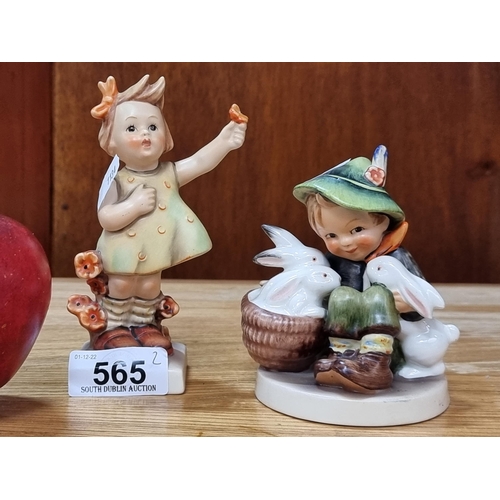 565 - Two Hummel figurines, one of a young girl holding flowers, and the other a young boy with his rabbit... 