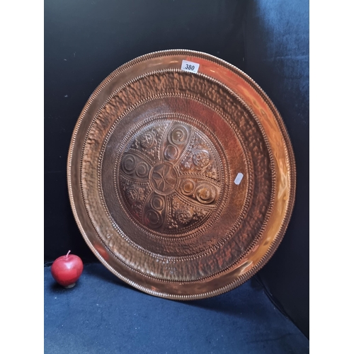 380 - A large, vintage, hand-hammered copper wall charger, with heraldic symbols and motifs. Diameter 56cm... 