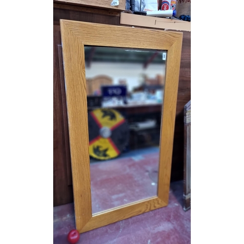 385 - A large wall mirror with wooden frame, can be displayed in either orientation. L122cm x W69cm.