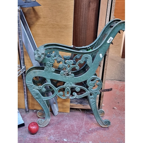 400 - A pair of antique, cast iron bench ends with curved lion head arm rests. In a green finish.