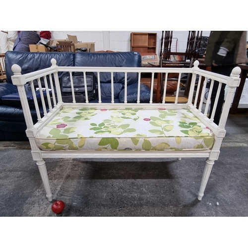 720 - A charming bench with reeded column back and sides, in a white finish. Seat cushion upholstered in a... 