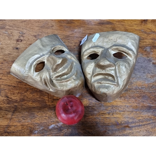 737 - Two hand crafted drama masks, featuring the classic happy and sad faces, in a gilt finish.