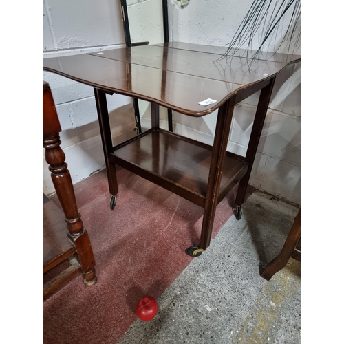 762 - A vintage drinks trolley with drop leaf sides, single tier to base all held on original rubber casto... 