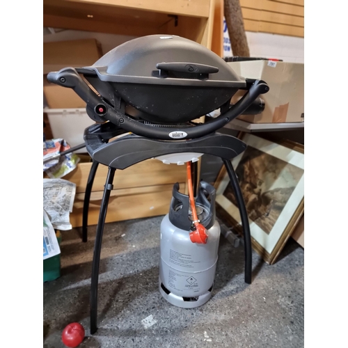 795 - An as new Weber branded barbeque (BBQ) grill. Model Q2000. With integrated stand and Calor Gas bottl... 