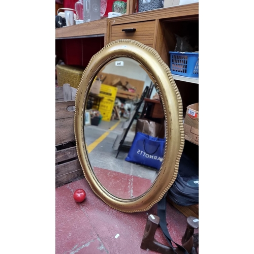 897 - An unusual wall mirror with a lightly, curved gilt frame with beaded detail. Containing a single pan... 