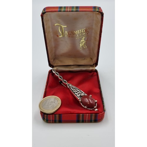 206 - A nicely designed kilt pin from Jacobite Jewellery of Edinburgh. Set with a dark pink gem and featur... 