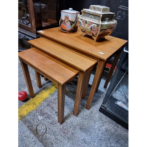 718 - A set of three mid century teak nesting tables. With a simple, geometric form and reeded detail.