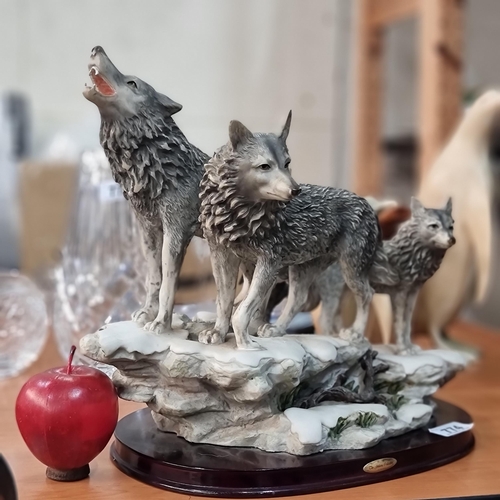 774 - A striking group figure of three wolves by The Juliana Collection. Mounted on a wooden base.