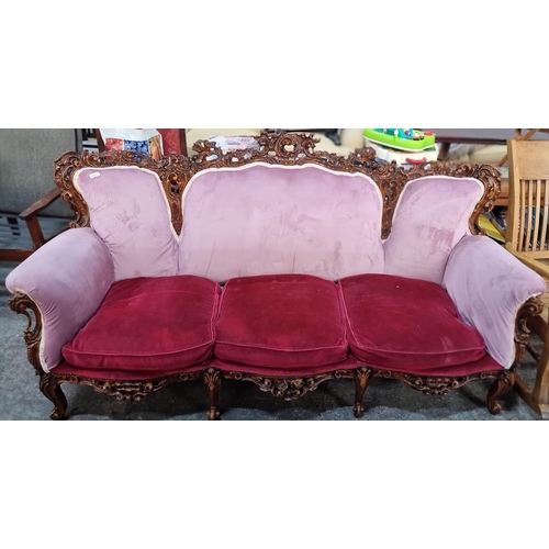 Star lot : A very striking three-seater sofa with a lavishly carved frame in high relief with a glossy lacquered finish. Upholstered in an unusual lilac and red plush fabric. A rally great looking piece. 
L200cm x D90cm x H105cm
