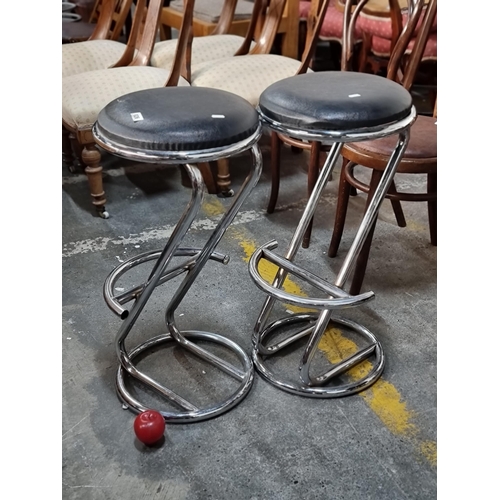 826 - A pair of sleek bar stool with padded black leather seats and curved chrome bases with footrests. H7... 