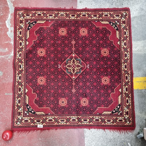 468 - A beautiful square hand knotted and handmade rug, in a rich shade of ruby with a geometric central v... 