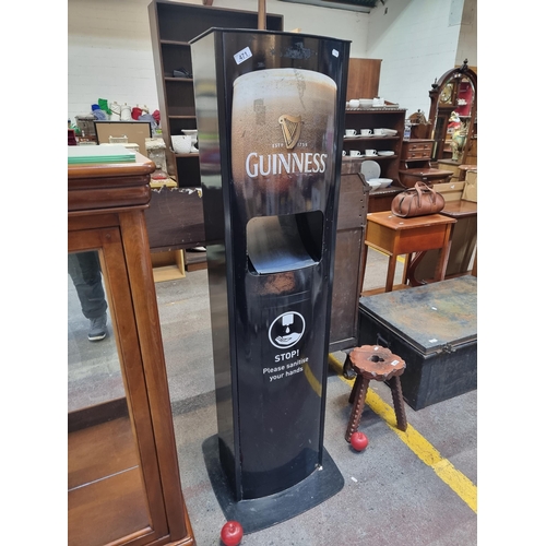 471 - A Guinness advertising public sanitiser stand. A free-standing unit in black with cream text, featur... 