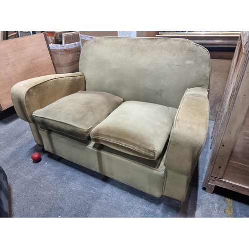 890 - An antique two seater sofa in an olive green, plush upholstery. Supported by ceramic castors. Starts... 