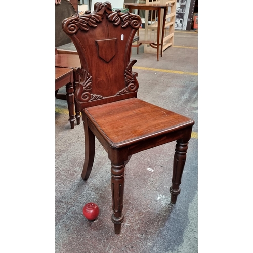 359 - A Victorian, mahogany shield back hall chair featuring acanthus leaf motifs and turned front legs. A... 