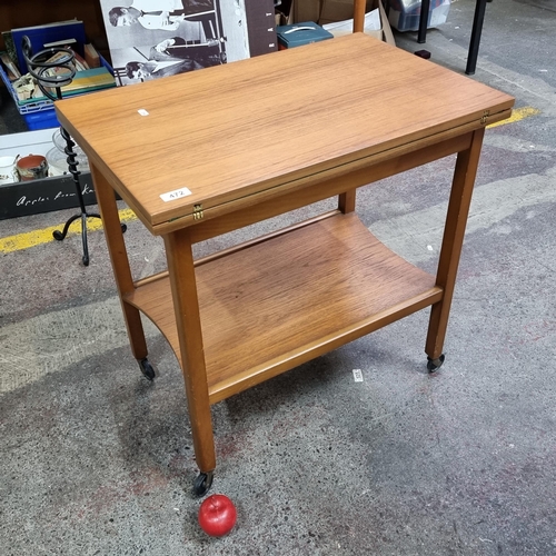 472 - A handsome mid century folding card table with green felt playing surface. Includes shelving space t... 