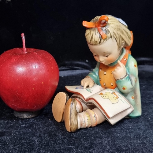 541 - A charming figure of a little girl reading a book by Hummel. In very good condition and stamped to b... 