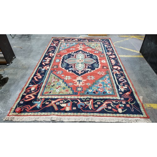 497 - Star Lot : A large Turkish wool blend rug from brand Lyric. In shades of red, navy blue, turquoise a... 