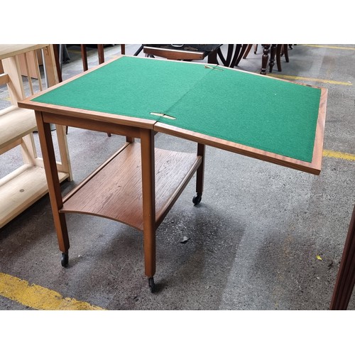 472 - A handsome mid century folding card table with green felt playing surface. Includes shelving space t... 