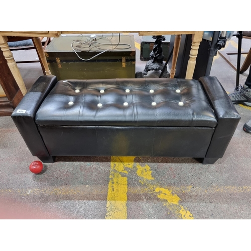 489 - A stylish bedroom bench upholstered in black leather with white button detail. The top opens to reve... 