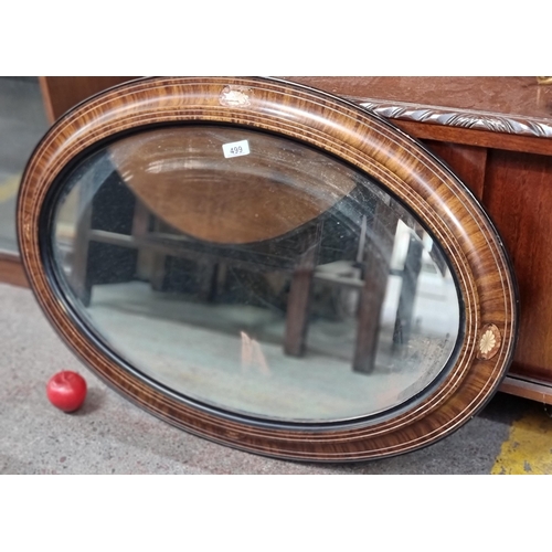 499 - A beautiful oval mantle mirror with beveled glass. Housed in a two tone wooden frame and black board... 