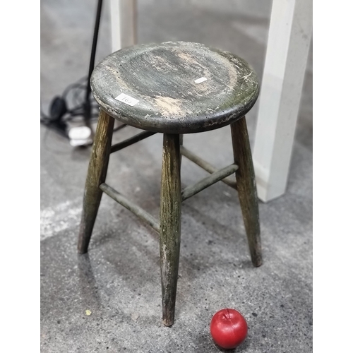 765 - A vintage stool with turned wood stretchers, in a rustic green finish.