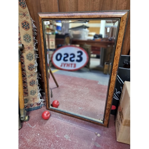 304 - A bevelled mirror with burl walnut styled border and gilt detail.  H85cm x W59cm