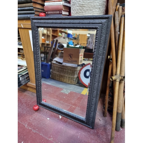 305 - A large bevelled mirror with relief acanthus leaf motifs and matte black finish. H110cm x W79cm Good... 