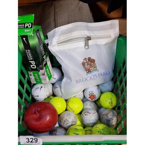 329 - A basket full of golf balls and a large number of golfing tees. Includes three Titleist Brocket Hall... 