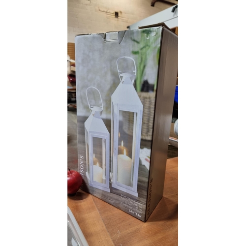 362 - A brand new set of two outdoor lanterns in a white finish, for use with pillar candles. Held in orig... 