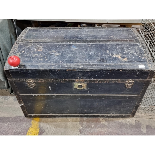 377 - A huge antique travel chest with domed top, metal reinforcements, leather handles and brass clasp. A... 