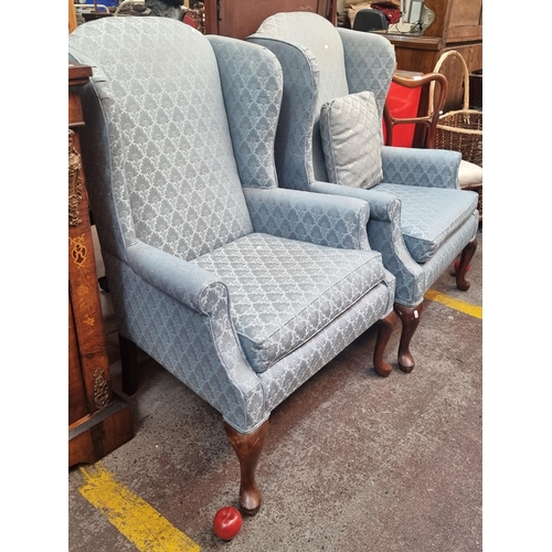 395 - Star lot : A pair of stylish wingback library  chairs with cushion seats and hoof legs.   Upholstere... 