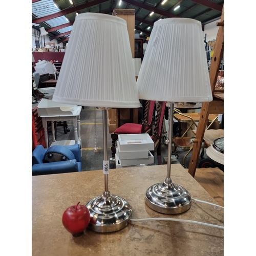 Two matching table lamps with chrome pedestal base and pleated white shades. from a UK design company.