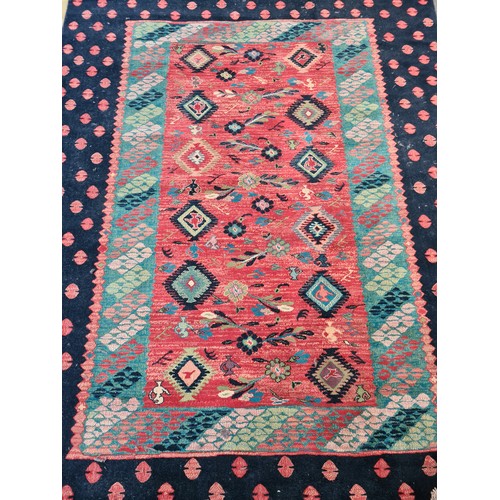 498 - A large Turkish rug in shades of red and blue and geometric design. With cream fringe L310cm x W200c... 