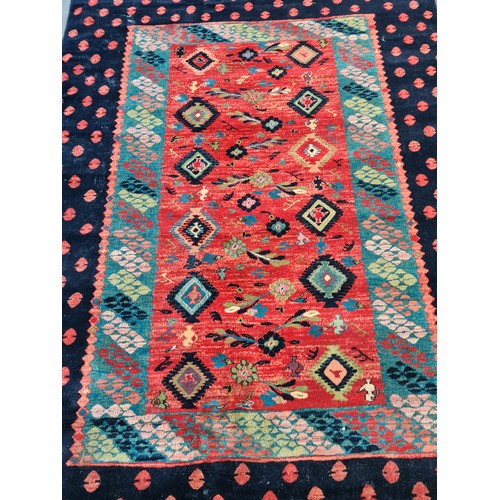 499 - A large Turkish rug in shades of red and blue and geometric design. With cream fringe L310cm x W200c... 