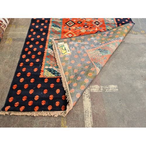 499 - A large Turkish rug in shades of red and blue and geometric design. With cream fringe L310cm x W200c... 