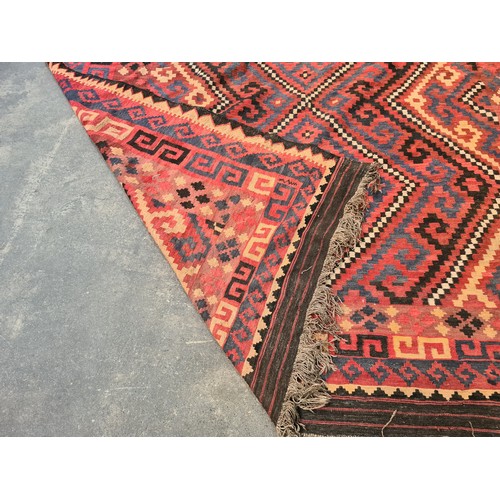 538 - Star lot : A very large handwoven wool floor rug with geometric pattern in bold shades of red, navy,... 