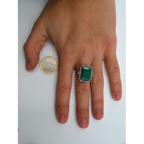 557 - Star Lot : A beautiful Emerald and Diamond ring, set with a halo of Diamonds which add to .45 carats... 