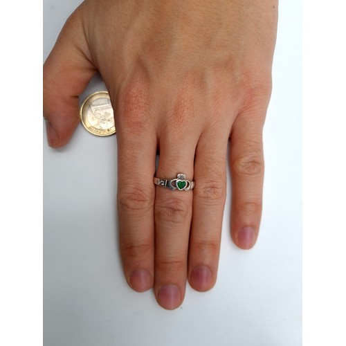 581 - A pretty example of a sterling silver Claddagh ring, set with a heart Emerald centre and gem stone m... 