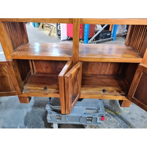 386 - A good red hardwood media unit. Including four shelves and two double door cupboards. Featuring unus... 