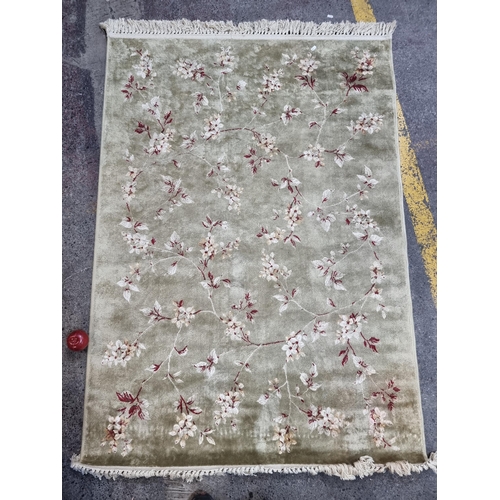 419 - An elegant floor rug in a silvery green by Antiqua. With delicate, red floral detail. L184cm x W120c... 