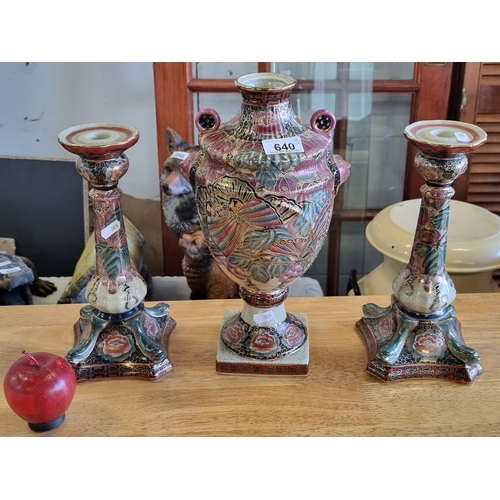 640 - Three very elaborate pieces of pottery, comprising of an urn and two candlesticks. Lavishly decorate... 